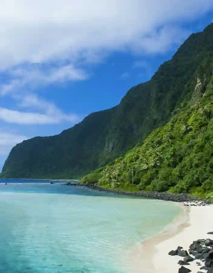 Höga gröna kullar som sträcker sig upp från havet och stränderna på Samoa