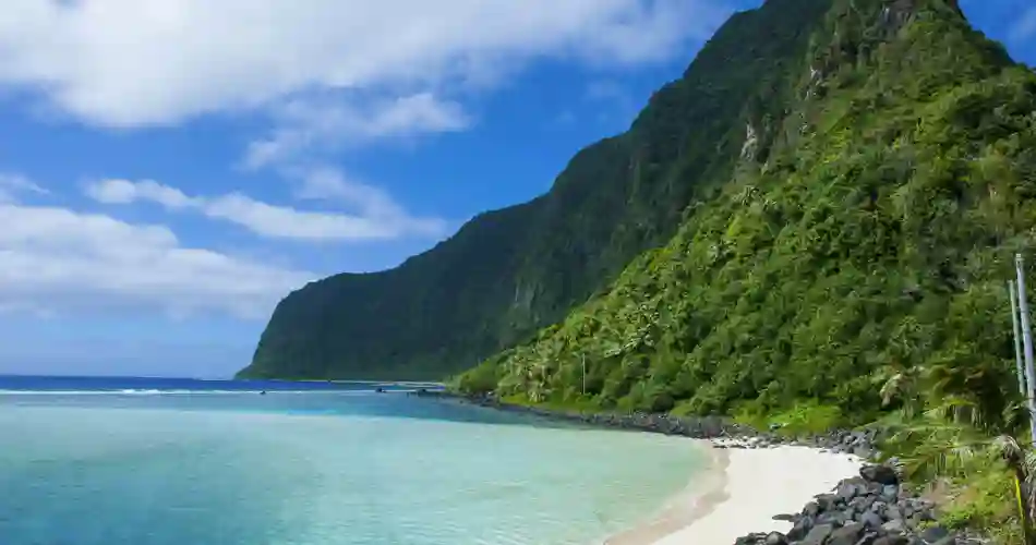 Höga gröna kullar som sträcker sig upp från havet och stränderna på Samoa