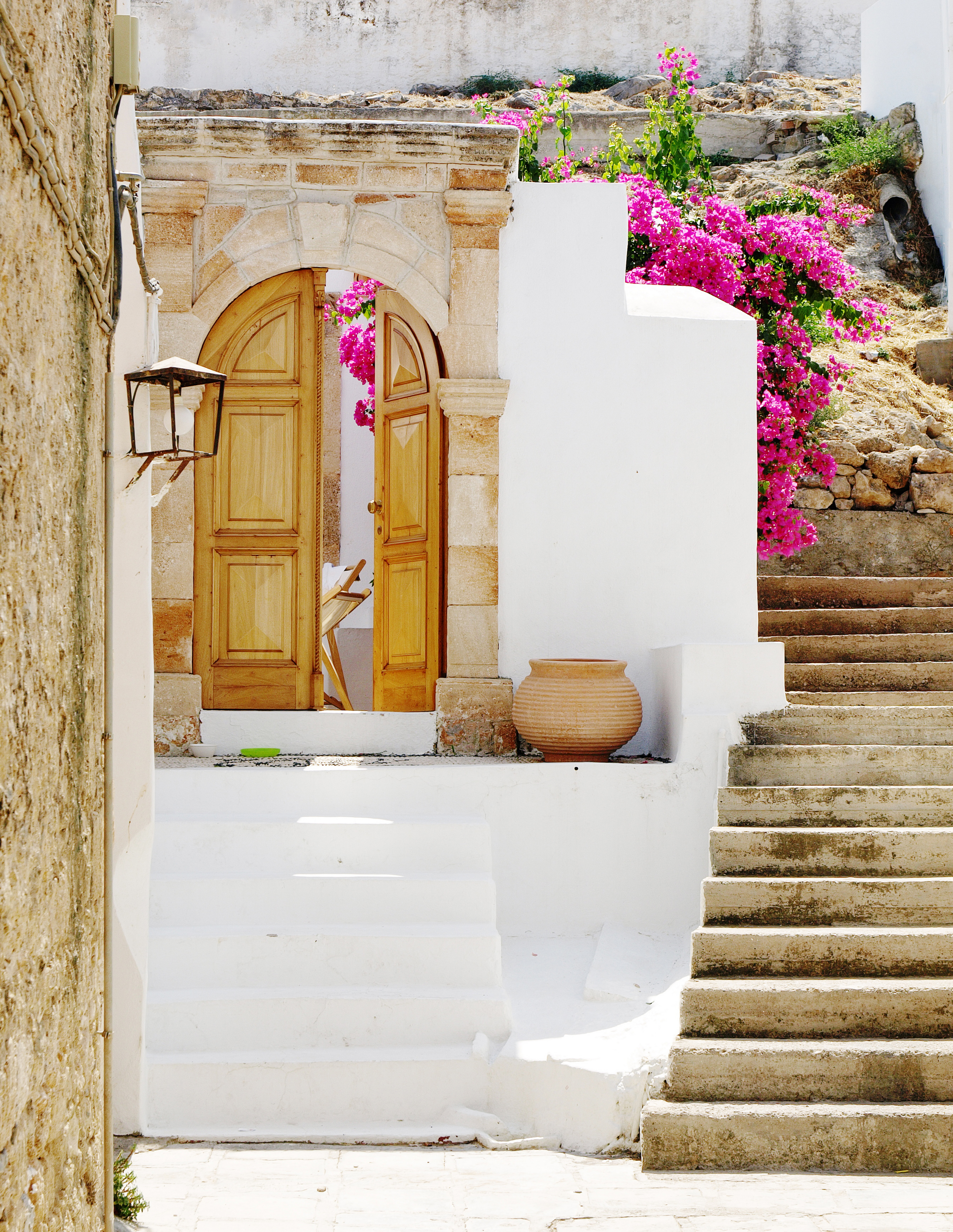 Vita stenhus, rosa blomster och vacker trädörr i Lindos på Rhodos