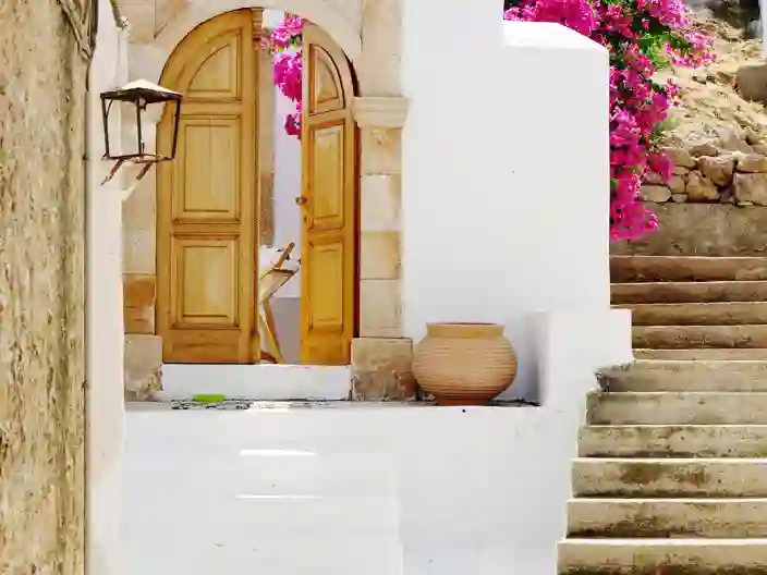 Vita stenhus, rosa blomster och vacker trädörr i Lindos på Rhodos
