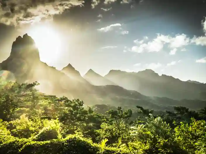 Solen står lågt bakom de gröna bergen på Moorea