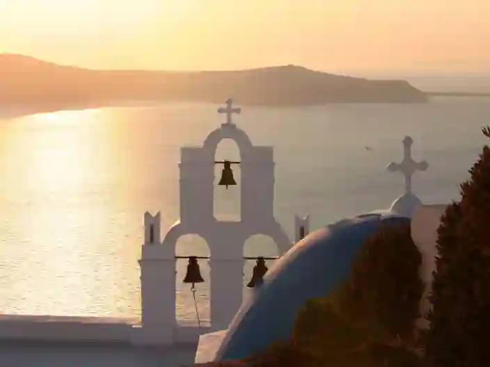 Vy över solnedgången och havet med vit kyrka på klippan i Santorini