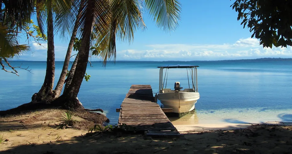 Båt vid lite brygga under palmerna i Bocas Del Toro
