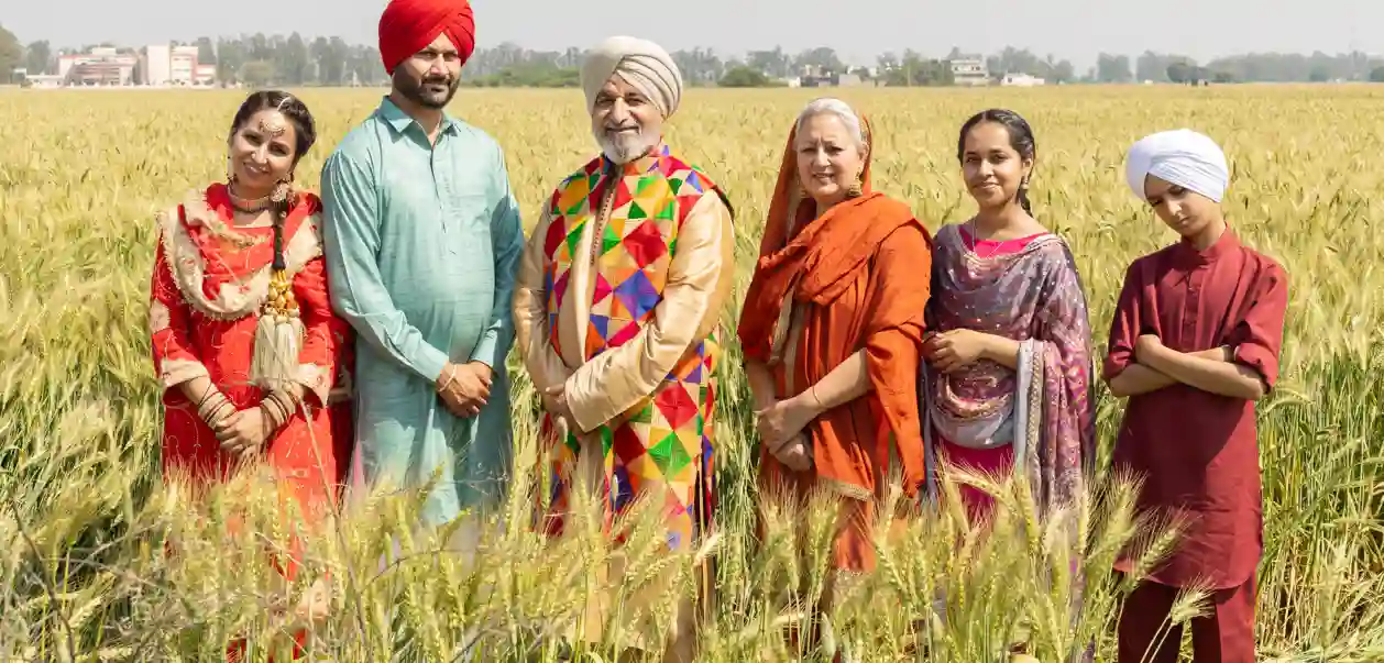 En punjabisk sikh-familie står sammen ude ved en mark iført farverigt tøj. Folk fra Punjab og Indiens kultur
