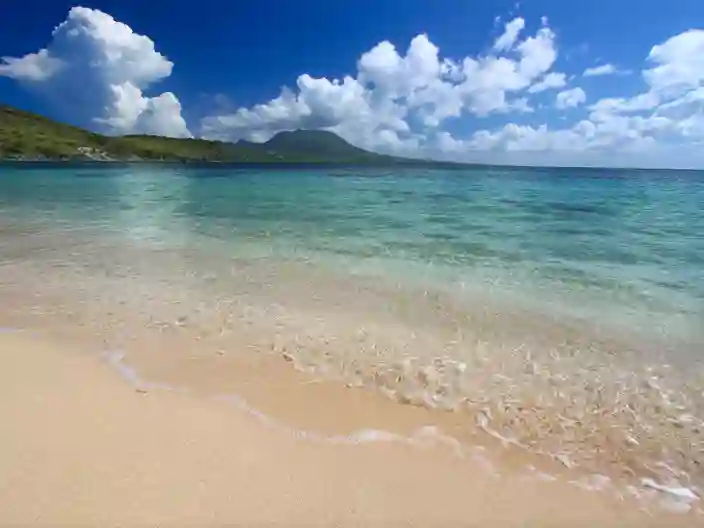 Strand i Karibien med klart vatten och gröna kullar
