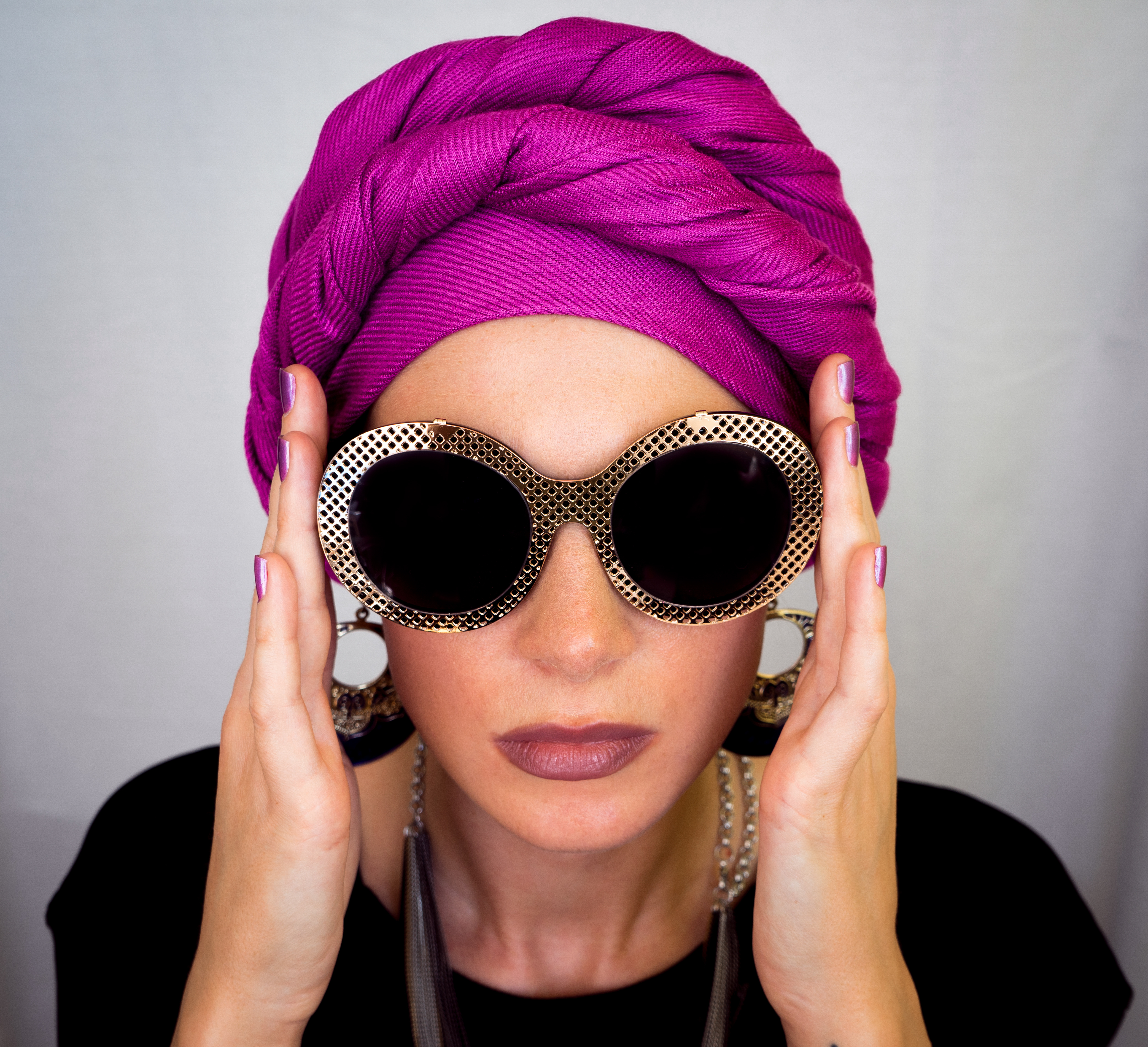 Europæisk kvinde i pink turban og store øreringe med runde briller. Urban fashion