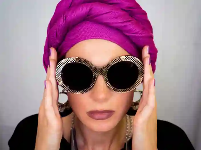 Europæisk kvinde i pink turban og store øreringe med runde briller. Urban fashion