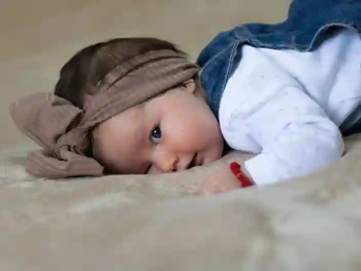 Nærbillede af en sød baby med turban, der ligger i sengen