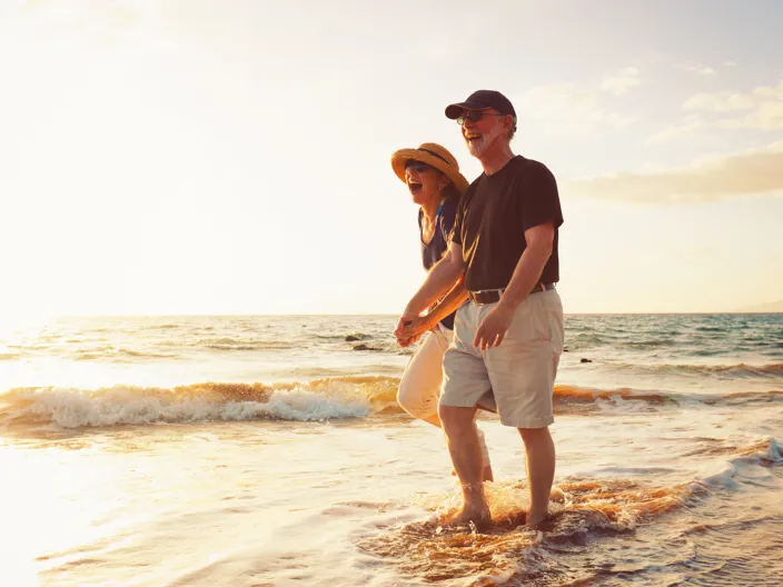 Skrattande par håller hand i vattenbrynet